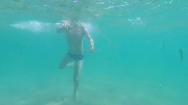 Çocuk denizde suyun altında yüzüyor. Su altı görüntüsü. Denizde yaz eğlencesi