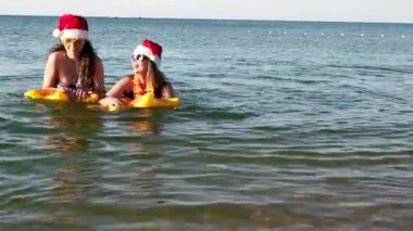 Anne ve kız Noel Baba 'nın Şapkaları içinde yüzüyor şişme yüzüklerle Yeni Yıl kutlamalarında. 
