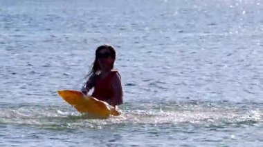 Kırmızı bikinili genç bir kadın denizde yüzüyor.