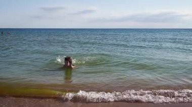 Genç çocuk denizde yüzüyor.