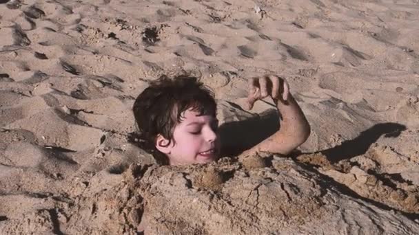 Een Jongetje Ligt Het Strand Begraven Het Zand Brunette Lachende — Stockvideo
