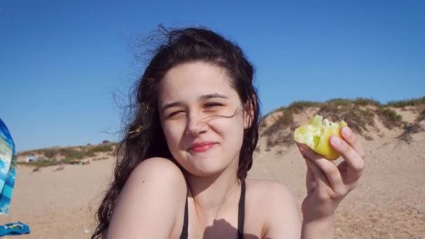 Brunette Tienermeisje Een Zwart Badpak Zittend Aan Zee Eet Gele — Stockvideo