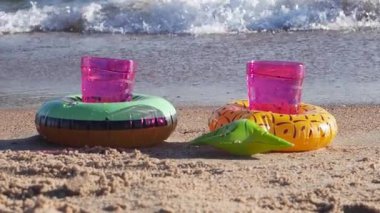 Dekoratif şişirilebilir bardak altlıklarında ozon bardakları denizin arka planında. Tasasız yaz tatili konsepti. Yavaş çekim