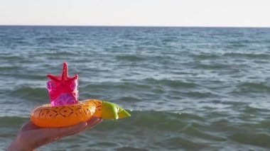 Bir adamın eli, deniz zemininde dekoratif şişirilebilir bardak altlığı içinde bir deniz yıldızıyla ozon camı tutuyor. Tasasız yaz tatili konsepti. Yavaş çekim