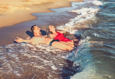 Kumsalın tadını çıkar, dalgaların tadını çıkar, orta yaşlı çift sahilde eğleniyor, çiftler deniz dalgalarının tadını çıkarıyor. Kumsalda gülüp duran bir çift esmer