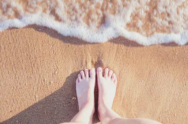 Okyanus sahilinde rahatla, dişi ayaklar deniz kumu üzerinde. Yaz tatili kavramı
