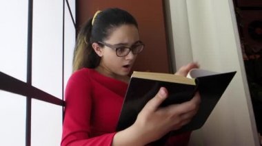 Gözlüklü esmer kız kitap okuyor, şaşırdı. 