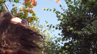 Kırmızı elbiseli ve ağaçların önünde güneş gözlüklü zarif bir bayan. 