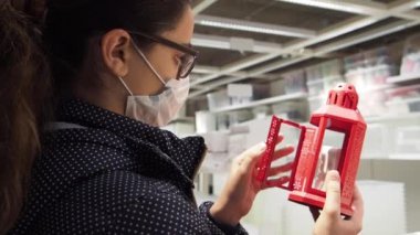 Genç esmer kız alışveriş merkezinde Noel süsü arıyor. 