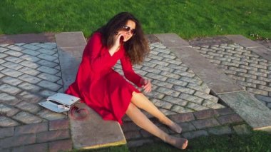 Kırmızı elbiseli, sarhoş ve zarif bir bayan merdivenlerde oturmuş, telefonla konuşuyor ve mezuniyetten sonra sendeliyor.