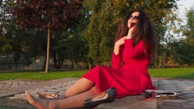 Kırmızı elbiseli, sarhoş ve zarif bir bayan merdivenlerde oturmuş, telefonla konuşuyor ve mezuniyetten sonra sendeliyor.