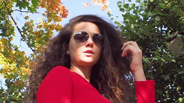 公園の赤いドレスとサングラスの上品な女性 — ストック動画