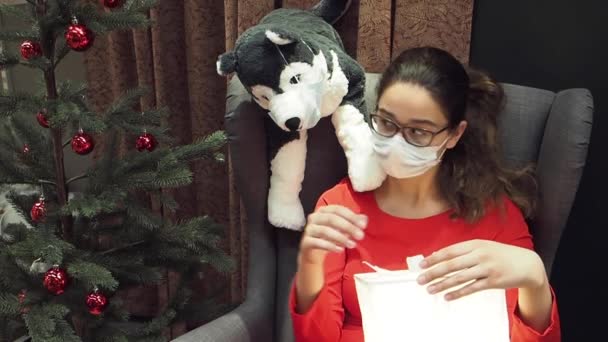 Молода Дівчина Брюнетка Масці Сидить Біля Ялинки Цілує Іграшкового Собаку — стокове відео