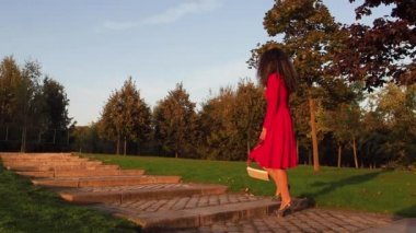 Topuklu ayakkabılı sarhoş kadın parkta yürürken ve düşerken beceriksiz.