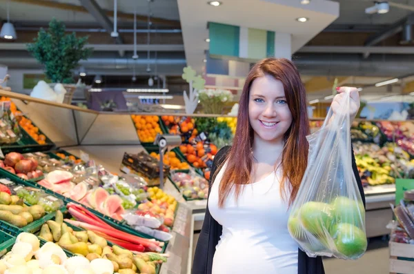 Hamile kadın ile polybag yeşil elma süpermarkette tutun