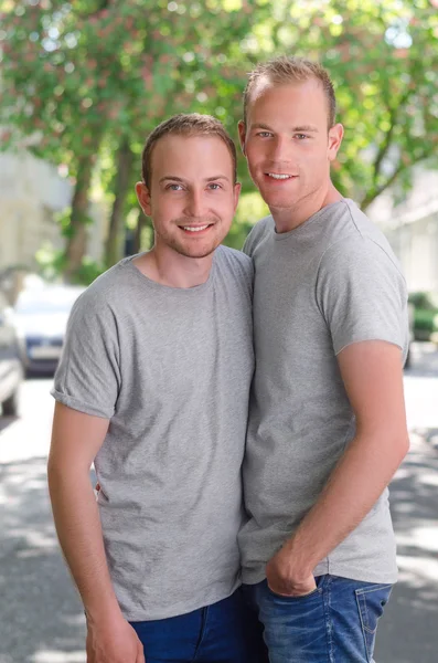 Dois homossexuais andando em uma rua na primavera, retrato como eles feliz sorrindo e abraçando — Fotografia de Stock