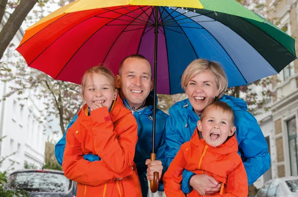 Gelukkig regen familie glimlach onder paraplu — Stockfoto