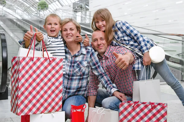 Başparmak gösterilen alışveriş merkezinde alışveriş torbaları ile aile 