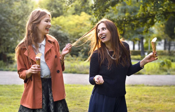 Två unga väninnor skrattar med glass — Stockfoto