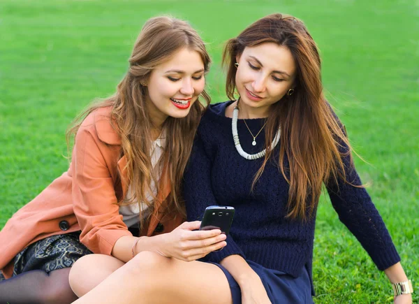 Två vänner tittar på en smartphone och leende — Stockfoto