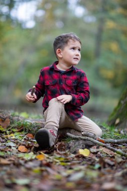 Ormanda yerde oturan küçük güzel çocuk dizini incitti.