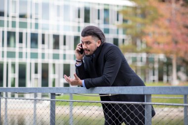 Köprüde telefonda konuşan yakışıklı genç adam.