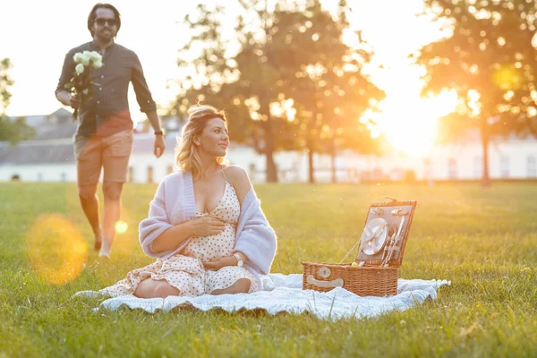 美丽的孕妇在日落时等着丈夫野餐 — 图库照片