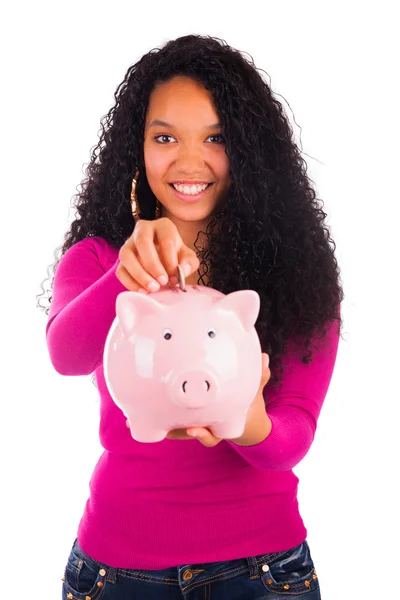 Young african american woman putting coin in piggy bank — Stock Photo, Image