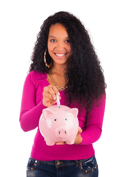 Young african american woman putting coin in piggy bank — Stock Photo, Image