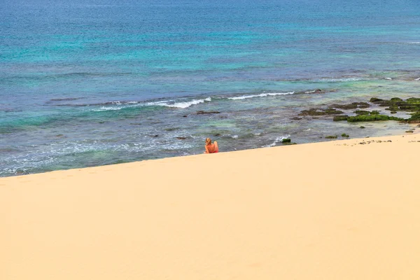 Mladá žena sedí na pláži, při pohledu na moře a nebe, B — Stock fotografie