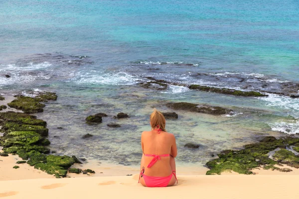 Młoda kobieta siedzi na plaży z widokiem na ocean i niebo, B — Zdjęcie stockowe