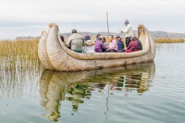 Uros yüzen ada yakınındaki bir kamış teknede ziyaretçi