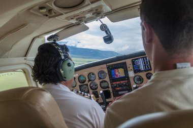 CANAIMA, VENEZUELA - AUGUST 16, 2015: Pilot of a small Cessna 210 Centurion airplane heading to Canaima village, Venezuela clipart