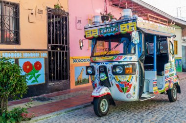 Guatape, Kolombiya - 2 Eylül 2015: Renkli mototaxi (tuk tuk) ve dekore edilmiş evlerde Guatape Köyü, Kolombiya