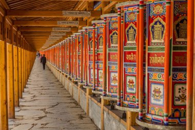XIAHE, ÇİN - 24 AĞUSTOS 2018: İnsanlar Çin 'in Gansu ilindeki Xiahe kasabasındaki Labrang Manastırı' nda bir sıra dua tekerleği geçiriyorlar