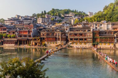 FENGHUANG, ÇİN - 13 AĞUSTOS 2018: İnsanlar Çin 'in Hunan bölgesindeki Fenghuang Antik Kasabası' nda Tuo Nehri 'nden karşıya geçiyorlar.