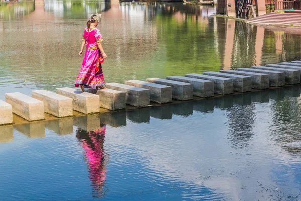 FENGHUANG, ÇİN - 14 AĞUSTOS 2018: Geleneksel giyinmiş kadın Çin 'in Hunan bölgesindeki antik kentte Tuo Nehri' ni geçiyor