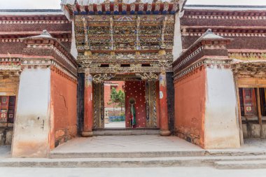 XIAHE, ÇİN - 24 AĞUSTOS 2018: Çin 'in Gansu ilindeki Xiahe kasabasındaki Labrang manastırının renkli oymalı kapısı