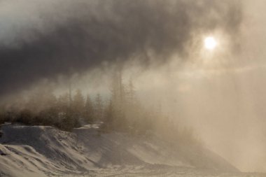 Kar topunun arkasındaki güneşin kış manzarası