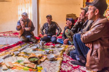 WAKHAN VALLEY, TAJIKISTAN - 22 Mayıs 2018: Yerel halk Wakhan Vadisi, Tacikistan 'da yerel bir evde çay ve atıştırmalık yiyor.