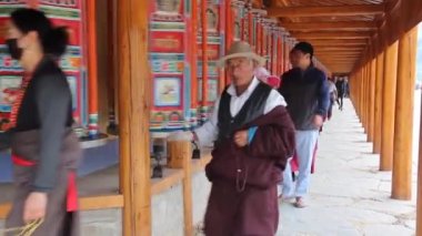 XIAHE, ÇİN - 24 AĞUSTOS 2018: İnsanlar Çin 'in Gansu ilindeki Xiahe kasabasındaki Labrang Manastırı' nda bir sıra dua tekerleği geçiriyorlar