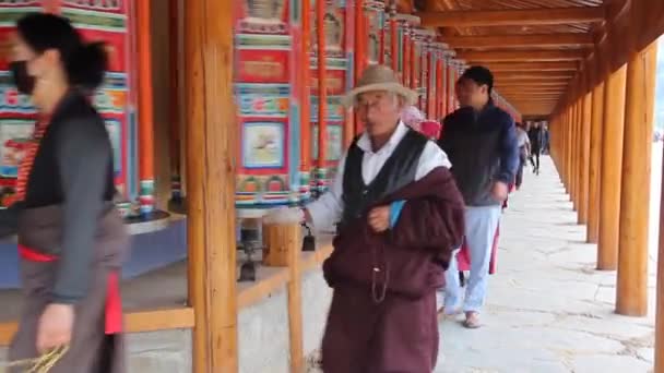 XIAHE, CHINA - 24. AUGUST 2018: Menschen passieren eine Reihe von Gebetsmühlen rund um das Labrang-Kloster in Xiahe, Provinz Gansu, China — Stockvideo