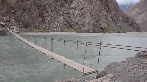 БАРТАНГ, ТАДЖИКИСТАН - 17 мая 2018 года: Человек, идущий по висячему мосту через реку Бартанг в Таджикистане Стоковый Видеоролик