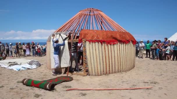 ISSYK KUL, KYRGYZSTAN - 15. června 2018: Místní lidé staví jurtu na etnofestivalu Teskey Jeek na pobřeží jezera Issyk Kul v Kyrgyzstánu — Stock video