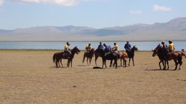 SONG KOL, KYRGYZSTAN - LIPIEC 25, 2018: Miejscowi grają kok boru ulak tartysh, tradycyjną grę konną, z kozim tuszem, na Narodowym Festiwalu Igrzysk Konnych nad brzegiem jeziora Son Kol — Wideo stockowe