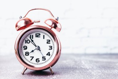 Zaman yönetimi kavramı için kopyalama alanı olan bulanık beyaz tuğla zemin üzerindeki klasik alarm saati