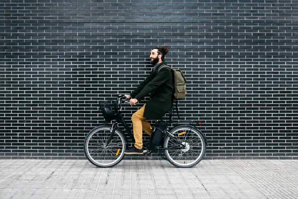 男子骑电子单车沿着砖墙 — 图库照片