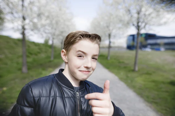 在公园里的十几岁的男孩举起大拇指 — 图库照片