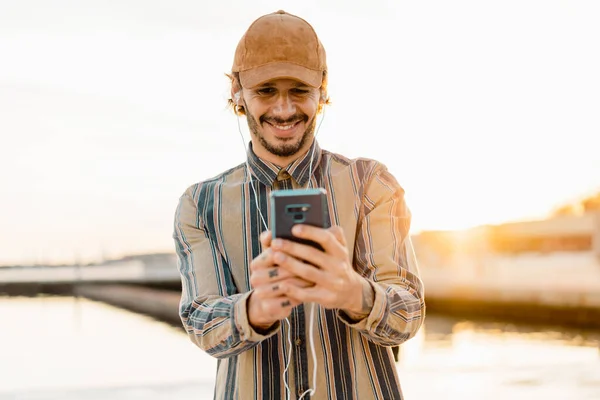 Portrait Smiling Man Wearing Baseball Cap Listening Music Earphones Smartphone — Stock Photo, Image