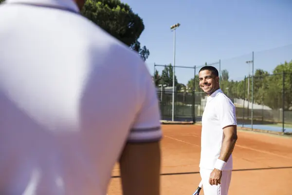 穿着运动服的人站在网球场上笑着看着庄稼的竞争对手 — 图库照片